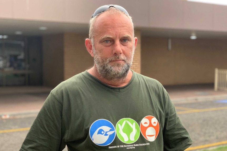 A man in a green t-shirt stands in front of a relief centre in Morwell.