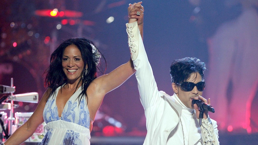 Sheila E raises Prince's hand as they perform onstage in 2007.