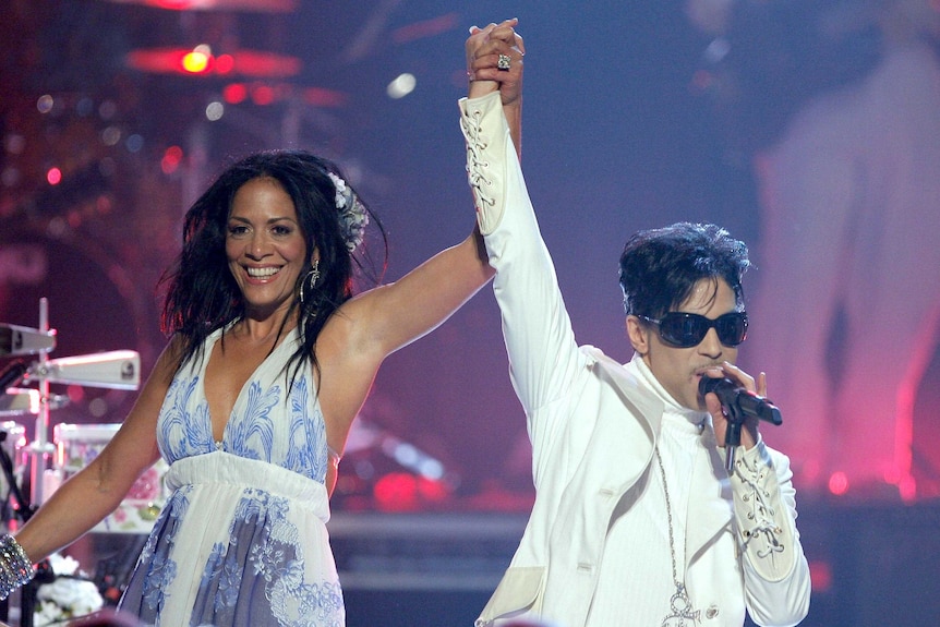 Sheila E raises Prince's hand as they perform onstage in 2007.