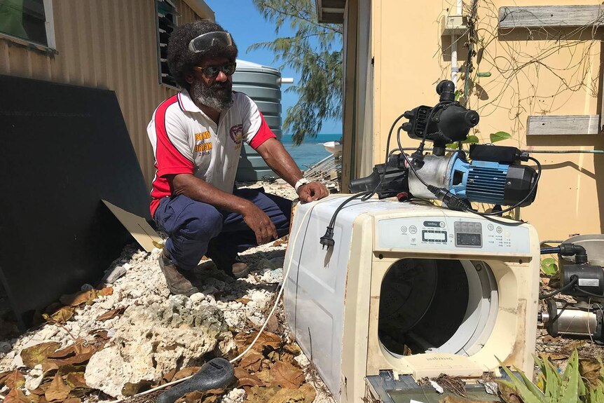 Ralph Pearson-Bann inspects his former washing machine that was picked up and dumped by the rising tide.
