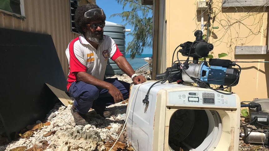 Ralph Pearson-Bann inspects his former washing machine that was picked up and dumped by the rising tide.