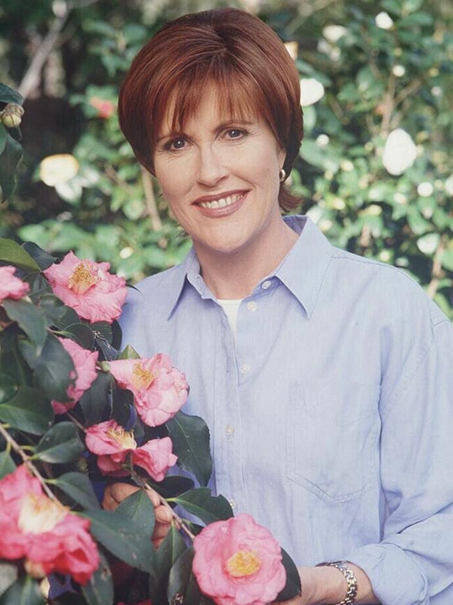 A woman stands next to flowers on a tree.