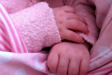 A baby's hands on a pink blanket