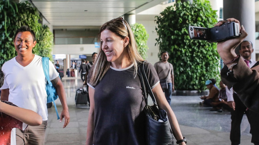 Mercedes Corby smiles as media film her exiting Bali's airport.