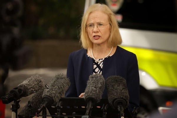 A woman with shoulder-length blonde hair speaks into a microphone.