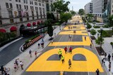 A view from above of a huge Black Lives Matter mural painted in bright yellow letters on a wide street
