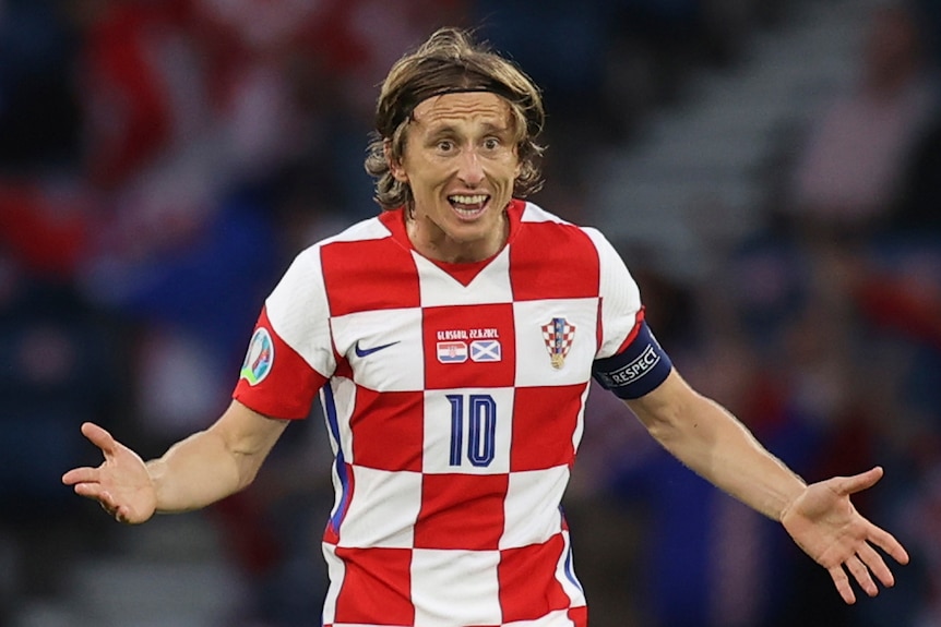 Luka Modric holds his hands up and looks surprised.