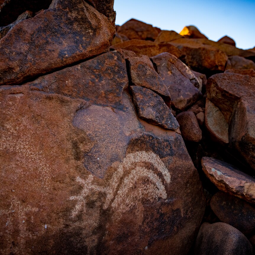 An interesting symbol is carved into a rock, amid a rocky landscape.
