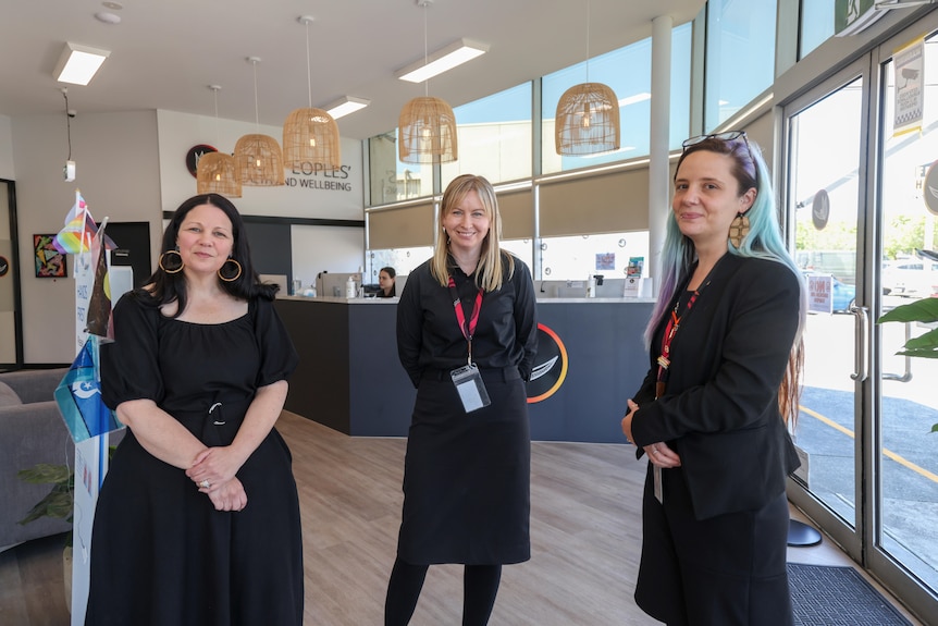 Three women wearing black stand in the lobby of a health centre.