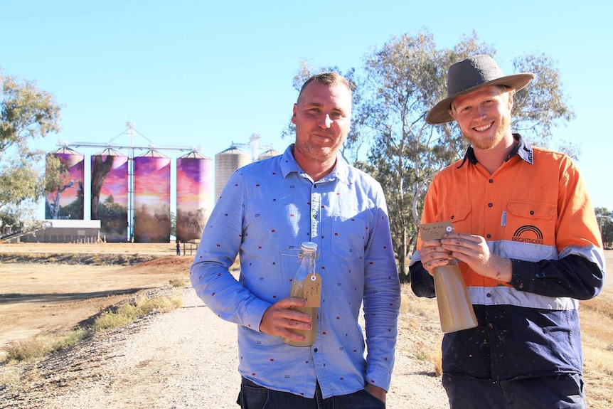 Brisbane street artists Travis Vinson and Joel Fergie hold 'the keys to city' of Thallon of Moonie River water.