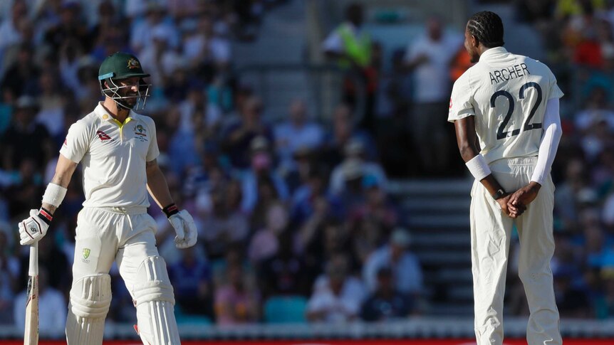 Australia batsman Matthew Wade looks at Jofra Archer, seen from behind, who has his hands behind his back.