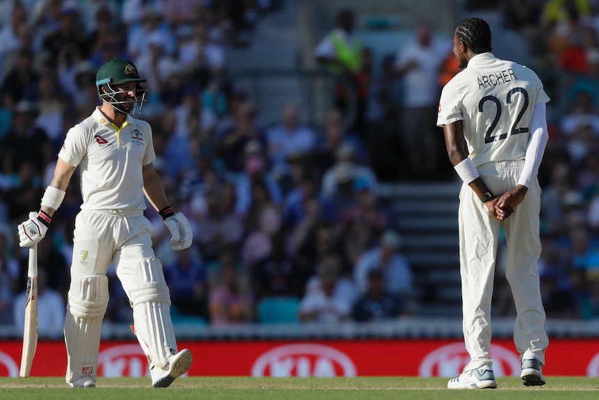 Australia batsman Matthew Wade looks at Jofra Archer, seen from behind, who has his hands behind his back.