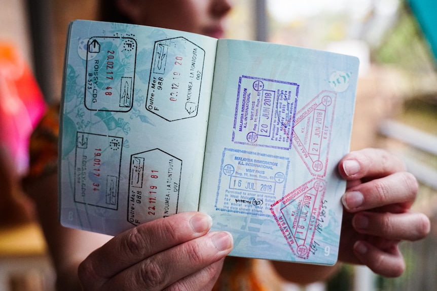 Hands holding a stamped passport.