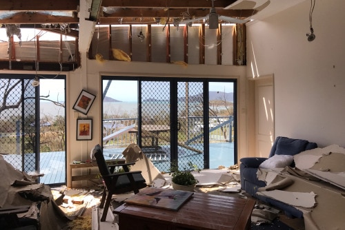 Inside a cyclone damaged home at Hydeaway Bay — the roof has been ripped off, furniture is strewn