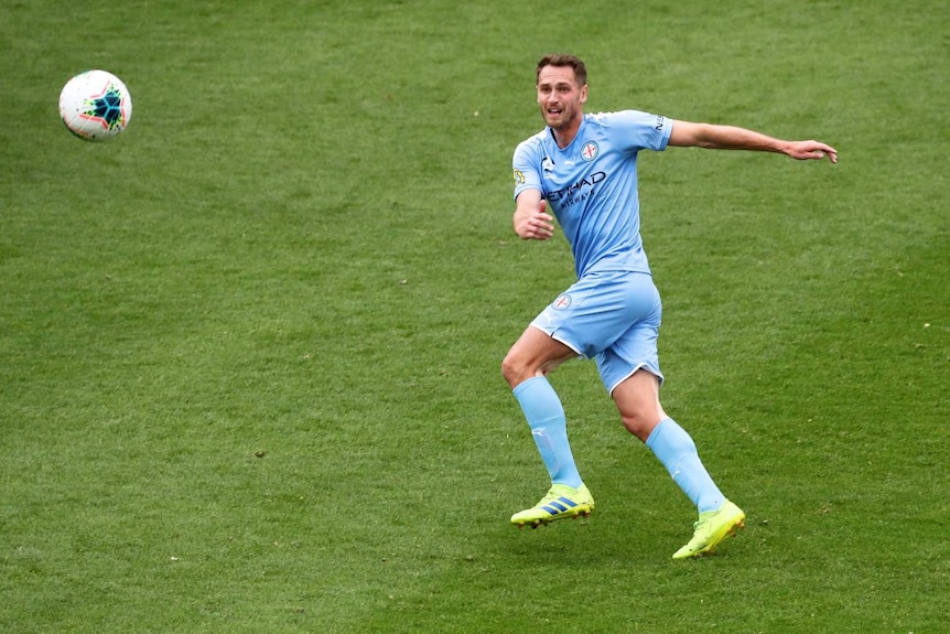 A soccer player prepares to trap a ball mid game on a soccer pitch