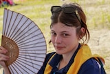 A girl waves a fan in her face.