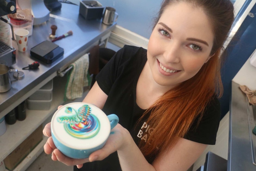 Emily Coumbis holds a Rainbow Coffee