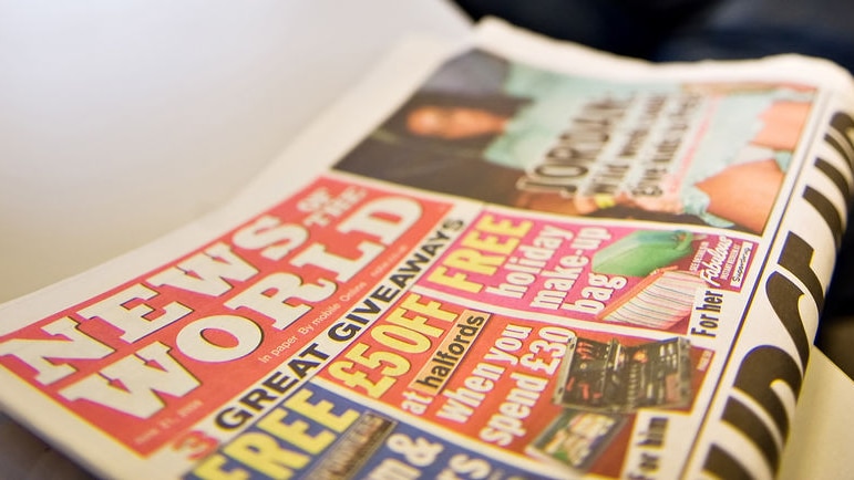 The News of the World newspaper sits on a desk.