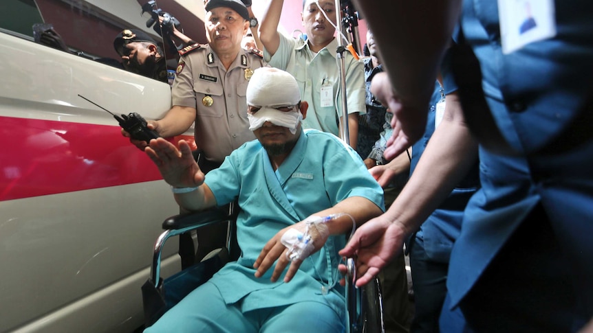 A man sits in a wheelchair as he leaves the general hospital, his head wrapped up in bandages.