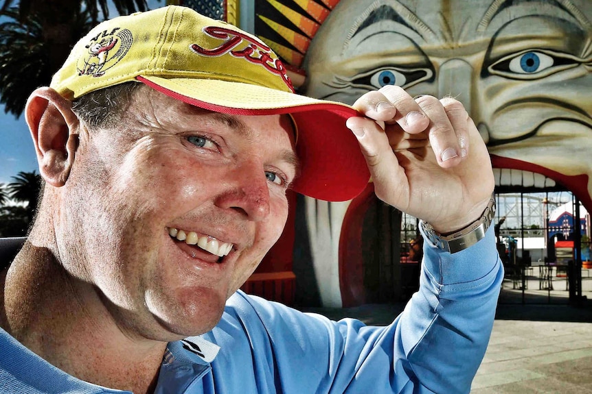 Jarrod Lyle smiles and tips his hat with the entrance to Luna Park in the background