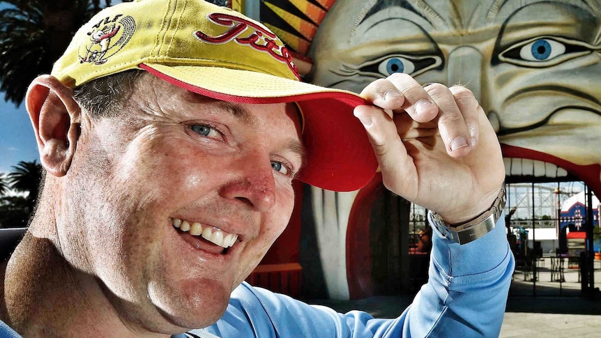 Jarrod Lyle smiles and tips his hat with the entrance to Luna Park in the background