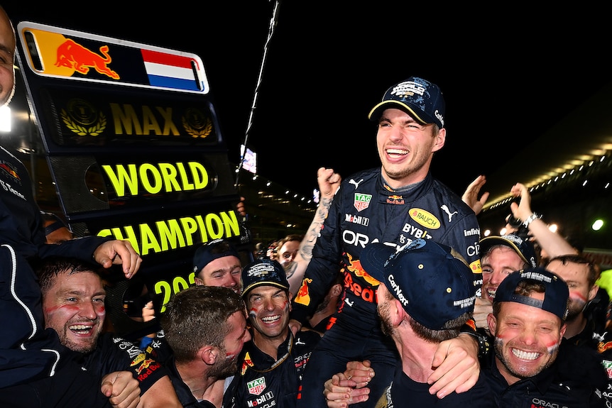 A man is hoisted on others shoulders in celebrations, with a sign which reads 'world champion'