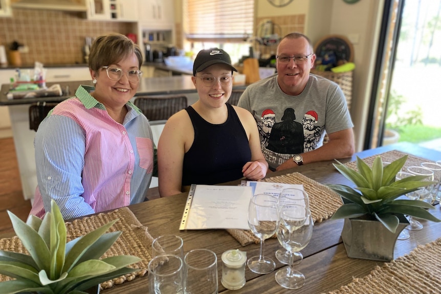 mum and dad sit beside their daughter at the family dinner table