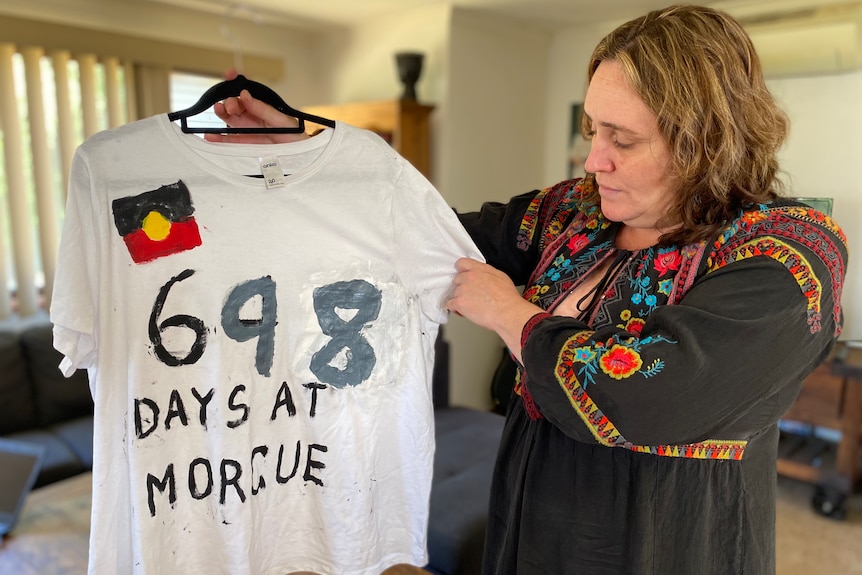 Woman holding up t-shirt that says 698 days at morgue