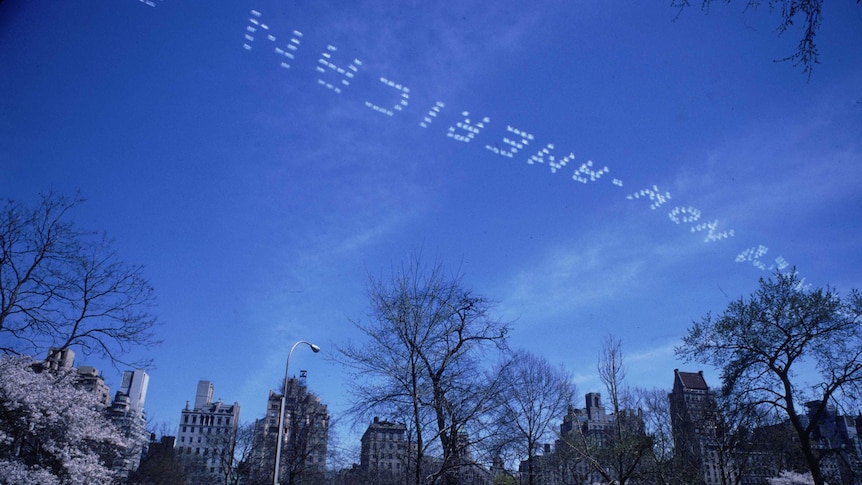 A skywriter trails a message across the sky over New York's Central Park, using the smoke trails of his aircraft to form words.