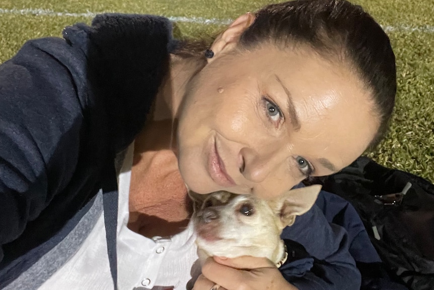 A selfie of Leisa Prescott with her dog at a sporting field.