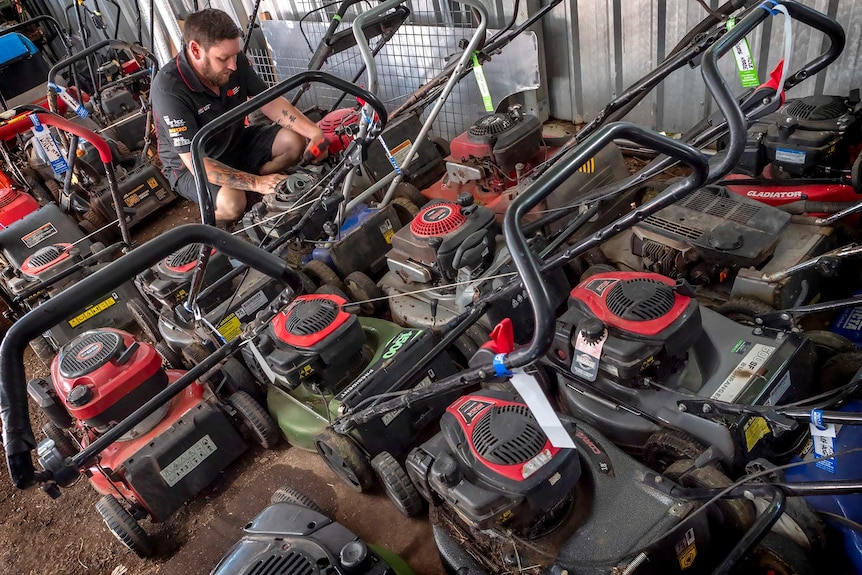 A man surrounded my lawn mowers.