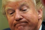 Donald Trump looks down with a grim smile