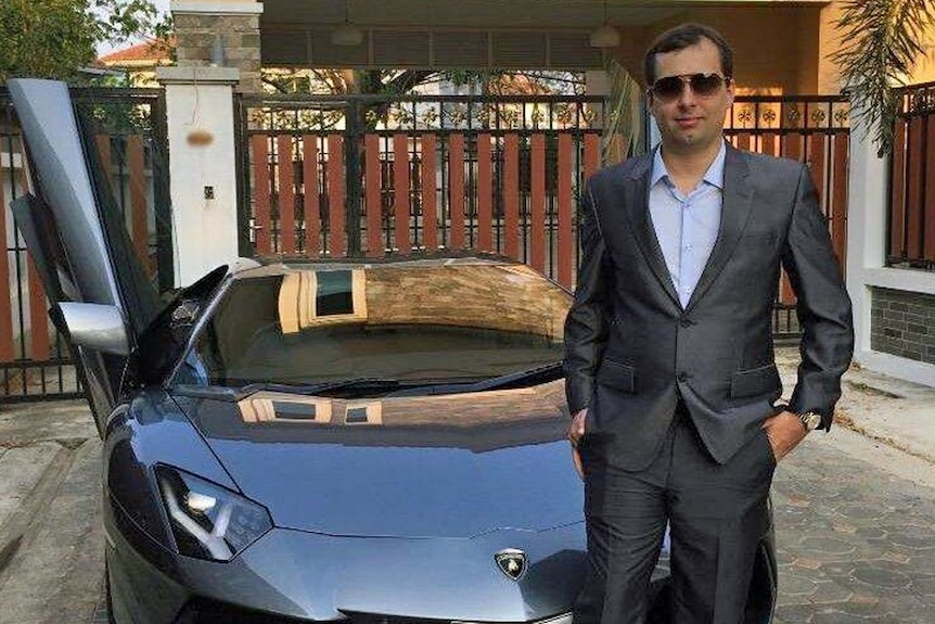 Alexandre Cazes poses for a photo next to a luxury car.