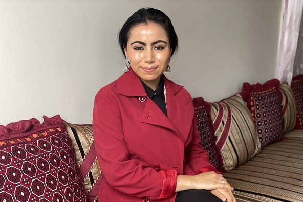 A photo of Sitarah, wearing red, sitting on a gold, black and red sofa.