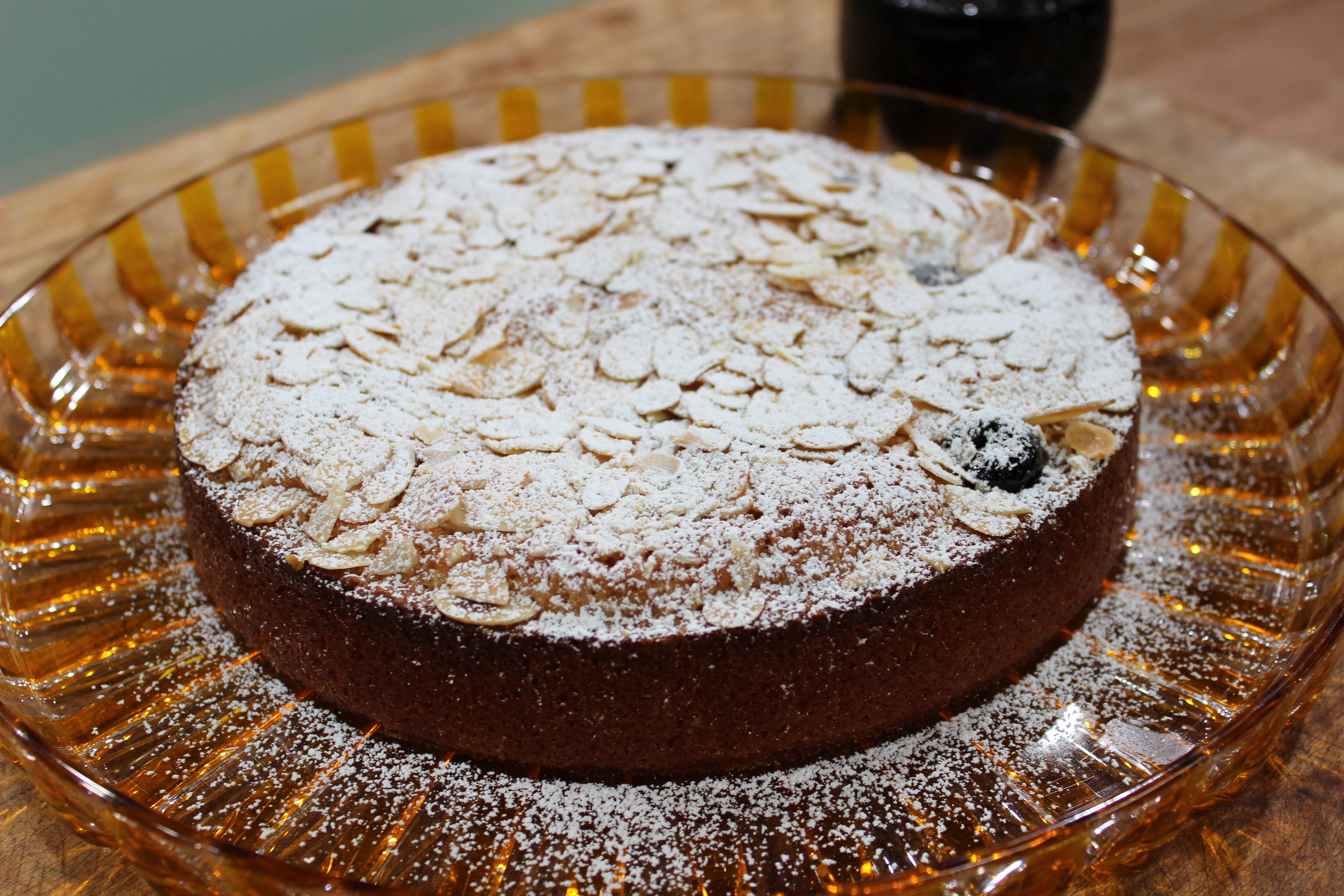 A picture of amaretto almond cake sitting on a tray dusted with icing sugar.