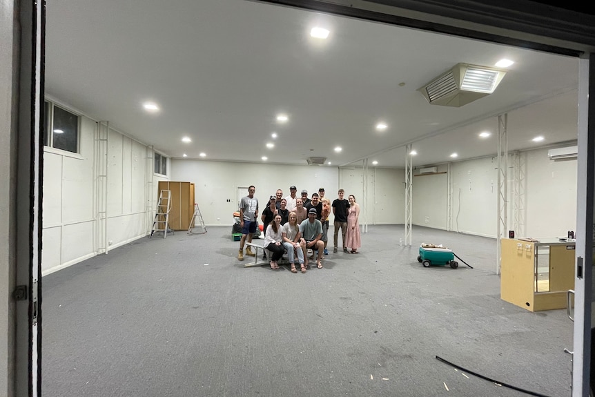 A group of people assembled for a group shot  in an empty shop