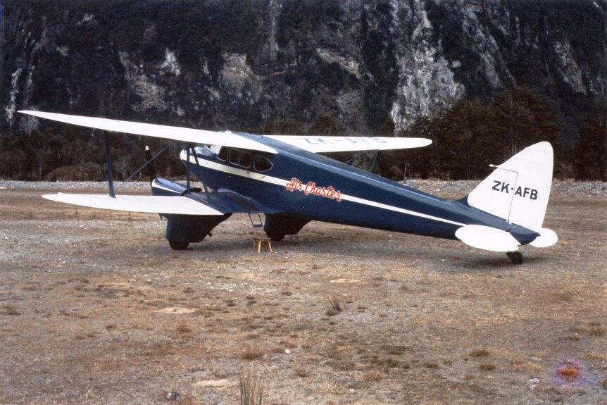 A film photograph of the blue and white aircraft parked up