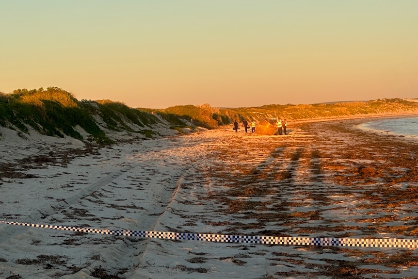 Police tape cordons off a section of beach where a cylindrical object sits