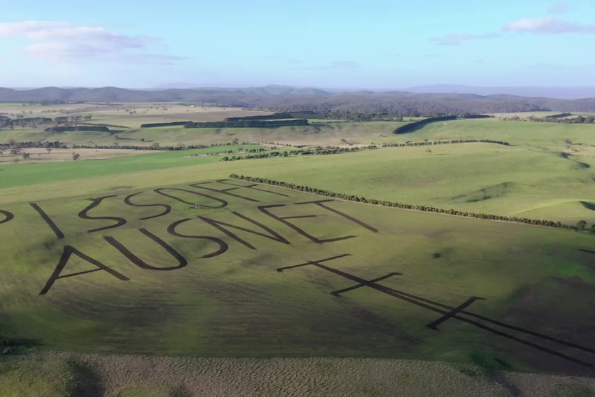 A drone photo of a western Victorian farm with a crude message written on it