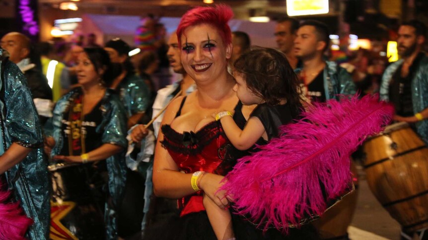 A woman holds a child at Mardi Gras.