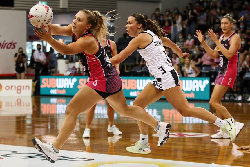 An Adelaide Thunderbirds Super Netball player leans to her left to catch a pass.