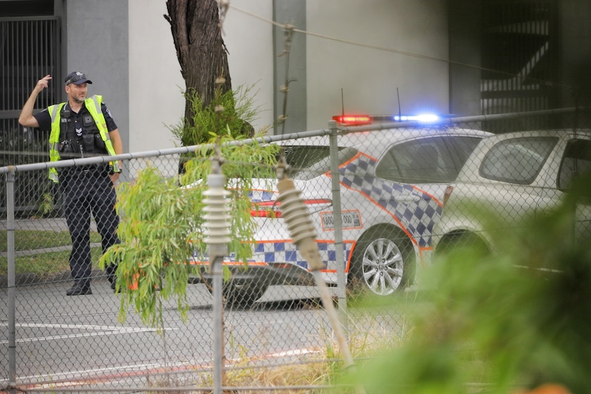 Queensland Police Service officer directing traffic past a road crash on Fairfield Road/Cardross Street, Yeronga