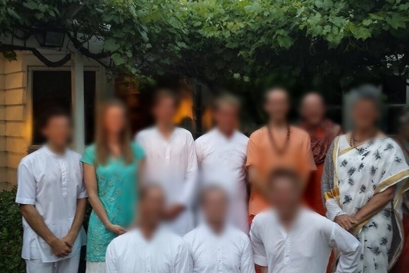 Ten members of the ashram community are pictured in Indian-style dress. Their faces have been blurred.