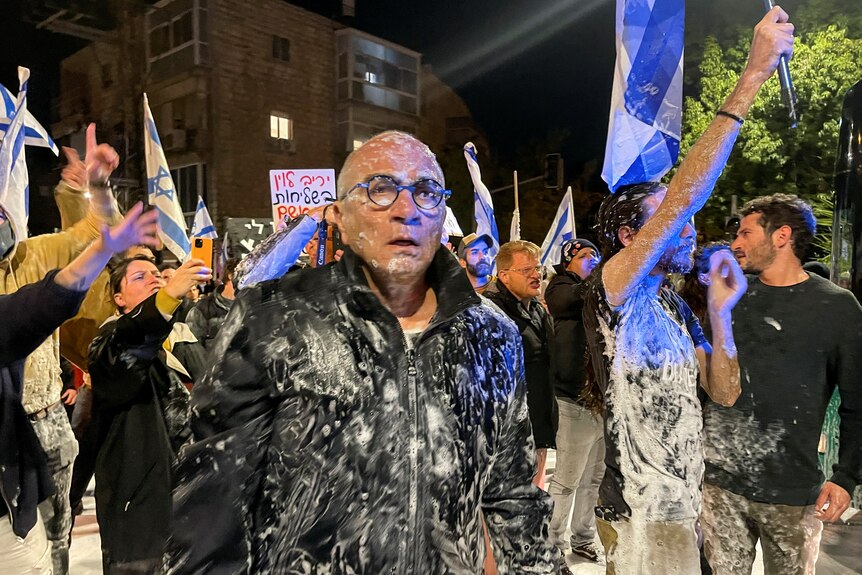 A man stands wet with water and soap in a protest in Israel.