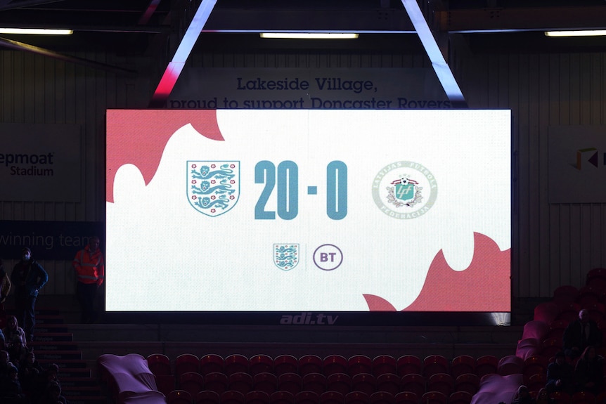 Emblems for England and Latvia's women's football teams are on a scoreboard during a World Cup qualifier with a 20-0 scoreline