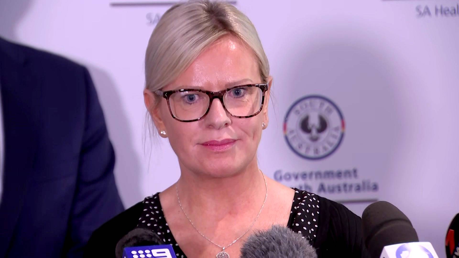 A mother stands in front of microphones at a media conference.