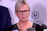 A mother stands in front of microphones at a media conference.