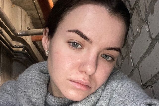 A woman takes a selfie looking upset in a bunker. 