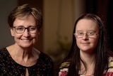 Two women, a mother and daughter, both wear glasses and smile.