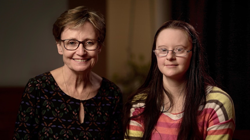 Two women, a mother and daughter, both wear glasses and smile.
